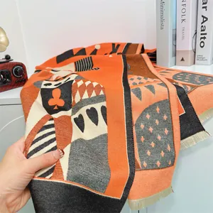 Detail of soft thick scarf with poker motifs, orange and black contrast, and tassels