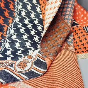 Detail of soft houndstooth scarf with chain and badge patterns and fringe edges