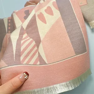 Close-up of thick knit poker pattern scarf fabric with pink and grey tassel details