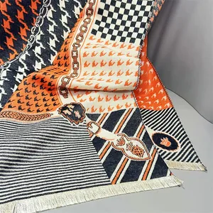 Detail of winter scarf showing plaid patterns, orange chain prints and soft tassels