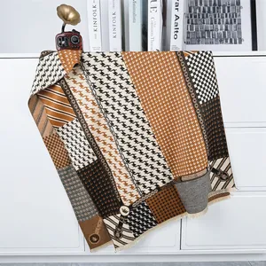 Detailed view of houndstooth scarf with tassels on a minimalist cabinet