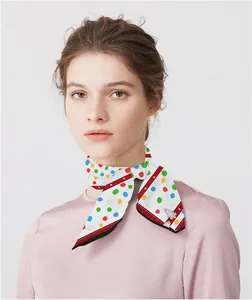 Close-up of a colorful polka dot silk scarf tied around a model's neck for styling