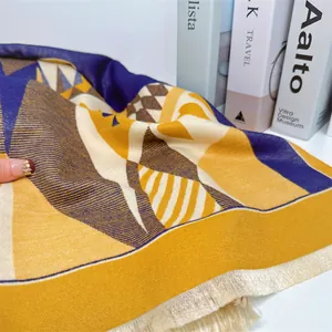 Detail of soft winter scarf featuring yellow and blue geometric patterns and fringe