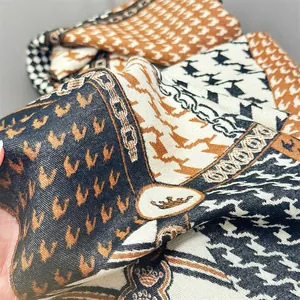 Detail of soft cashmere-feel scarf featuring houndstooth, chain patterns, and crown motifs