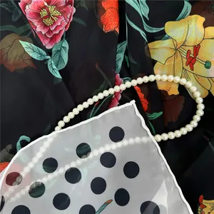 Elegant white pearl necklace on floral print and black polka dot georgette silk scarf