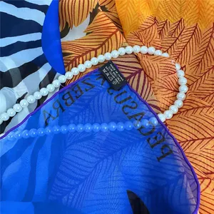 Close-up of 100% silk square scarf featuring tropical palm leaves and zebra print textures