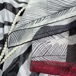 Detail of georgette shawl with zebra print and red feathers next to pearls