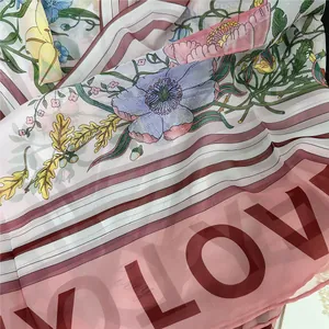 Dettaglio di sciarpa in chiffon floreale con stampa LOVE e bordo a righe elegante