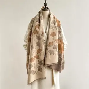 Macro shot of faux cashmere scarf featuring brown ginkgo leaf prints and fine fringe edges