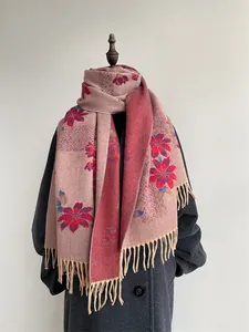 Detail of pink floral cashmere scarf with elegant tassels on a grey wool coat display