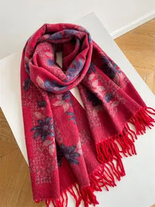 Detailed view of thick red floral knit scarf with elegant fringe tassels on white surface