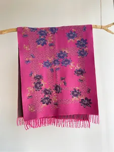 Detailed view of floral pattern on pink cashmere scarf with fringe hanging on branch