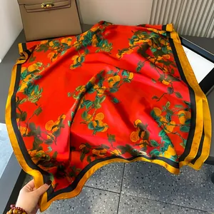 Elegante sciarpa in seta rossa con stampa di frutta e bordo dorato a contrasto sul tavolo