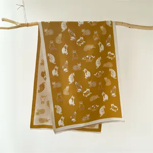 Detail van de mosterdgele sjaal met schattige kattenprints en fijne franjes aan hout
