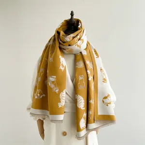Detail van een dikke wintersjaal met kattenpatronen en franjes in gember en beige