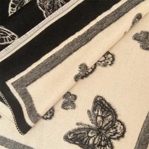 Detailed close-up of thick cashmere scarf featuring intricate butterfly patterns and fringes