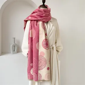 Close-up of bohemian pashmina shawl with grey-pink geometric patterns on a beige coat