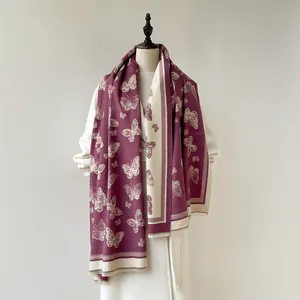 Detail view of burgundy and cream scarf featuring butterfly jacquard and fringe edges