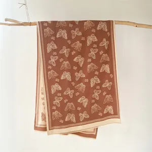 Close-up of caramel brown and cream cashmere scarf with butterfly jacquard patterns