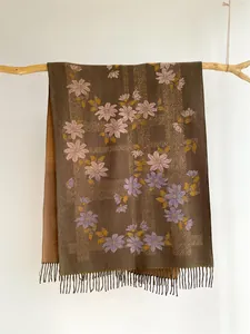 Detail of dark brown floral cashmere shawl with pink flowers and fringe on wood branch