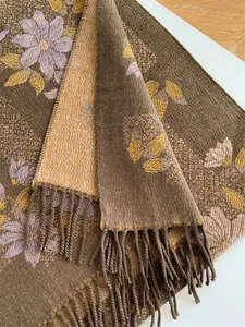 Close-up of floral jacquard patterns and twisted rope tassels on a warm brown shawl