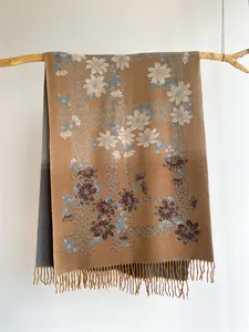 Close-up of floral jacquard knit scarf with daisy patterns and soft fringe detail