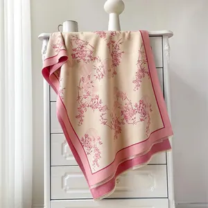 Elegant beige cashmere-like scarf with pink floral patterns and delicate tassels