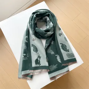 Detailweergave van het dubbelzijdige kattenjacquardpatroon en zachte franjes aan de sjaal