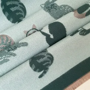 Gedetailleerde macro-opname van de dikke pastelgroene sjaal met schattige kattenjacquard