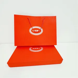 Detalle de caja de regalo roja texturizada y bolsa con asas tejidas para bufandas