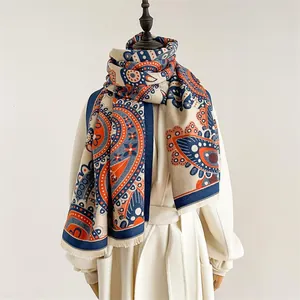 Détail d'un châle en cachemire beige avec motifs paisley orange et fines franges