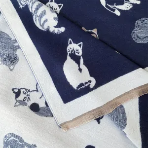 Detail van de dubbelzijdige gebreide sjaal met kattenpatronen en franjes aan de randen