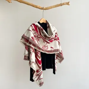 Détail d'un châle floral aux motifs rouges vintage et bords à franges sur un cintre