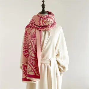 Détail d'une écharpe en cachemire rose et beige avec motif paisley et franges élégantes