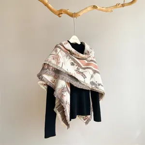Détail du motif floral vintage et des franges sur une écharpe crème en cachemire
