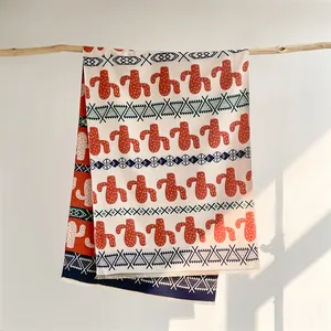 Detail of cashmere-like shawl featuring cactus print and tassels on a wooden branch