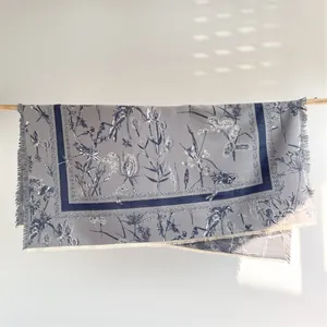 Détail d'une écharpe florale gris et bleu avec motifs botaniques et bords à franges douces