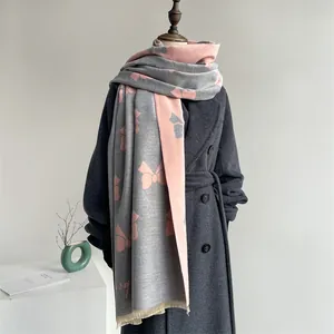 Detail of grey and pink bow print shawl with fringe on a dark wool coat