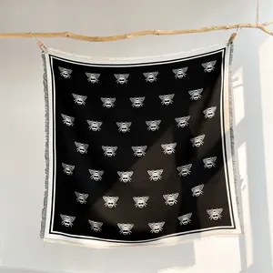 Close-up of black and white bee pattern scarf with fringe trim and soft wool texture