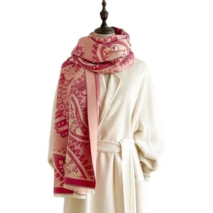 Écharpe élégante rose à motif cachemire avec franges sur un manteau blanc pour l'hiver