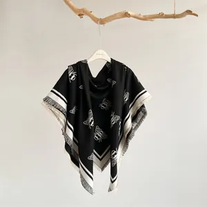 Detail of black and white bee patterned pashmina shawl with fringe edges on wood