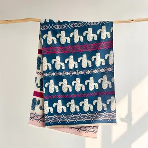 Detail of cashmere-like scarf with blue cactus print and ethnic border on wood branch