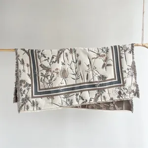 Détail du motif floral et libellule sur une écharpe crème chaude à franges