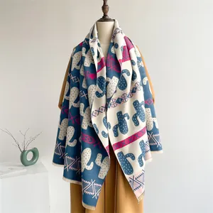 Close-up of cashmere-like scarf with ethnic cactus prints and navy tassels on a coat