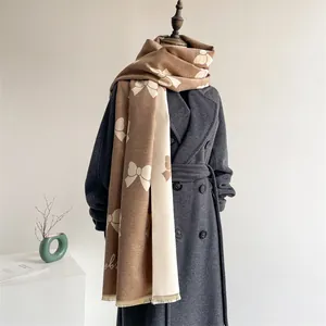Close-up of khaki and cream scarf with bow pattern, fringe details on wool coat