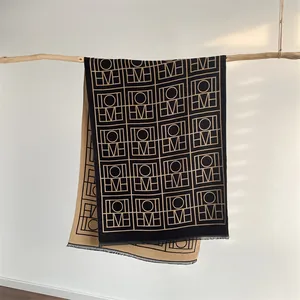 Détails de motifs jacquard géométriques sur une écharpe épaisse réversible en cachemire