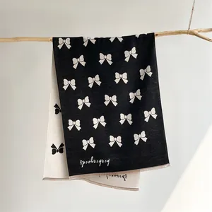 Close-up of double-sided bow print scarf featuring frayed edges and thick warm material