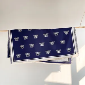 Detail of navy blue cashmere-feel scarf with white bee prints and tassel edges