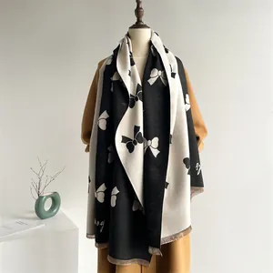 Detailed view of black and white bow pattern scarf with fringe on model coat