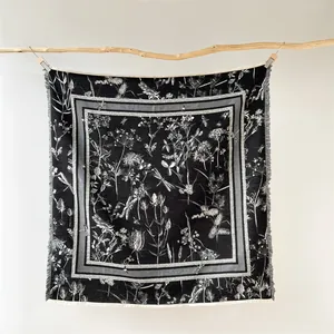 Détail d'un foulard carré vintage à motifs floraux avec des bords effilochés